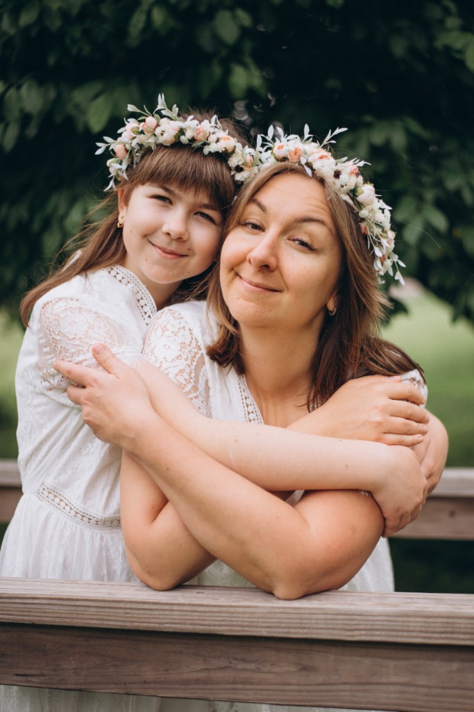 Ludmila and her daughter Maria together, wearing white lace dresses and flower crowns